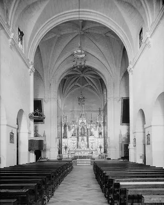 Black and white church interior with pews and alter.