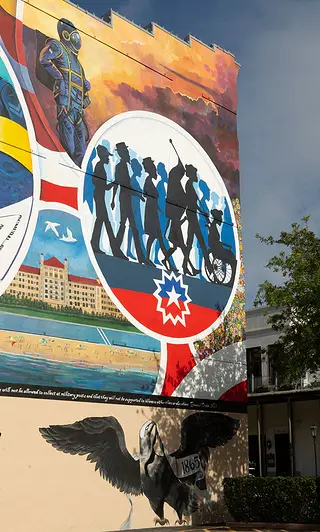 A detailed view of the mural Absolute Equality. This view shows a circle featuring a group of silhouetted people walking, while in the foreground is a building and a person in a spacesuit in the background.. 