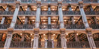 View of a multistory library with each alcove featuring a gorgeous metal work railings and carefully designed columns and archways. 